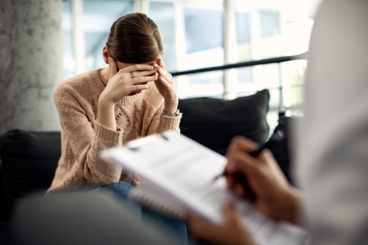 Image of a woman looking down recounting a painful issue during a counseling session.